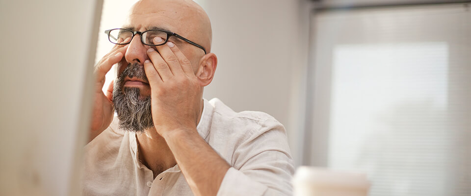 Stressed man with glasses rubbing his eyes