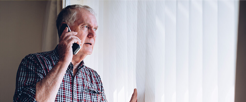 Old man looking out window on the phone